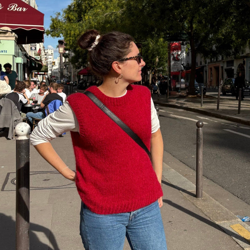 femme portant un pull sans manches rouge tricoté à la main dans la rue