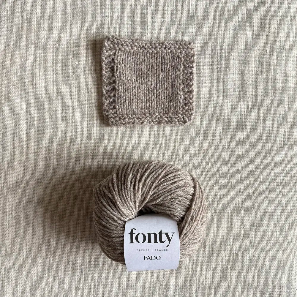 Pelote de laine Fado coloris beige chiné de Fonty – boutique Tricotant, vue de dessus sur fond lin avec échantillon tricoté