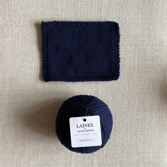 Pelote de laine Mérinos coloris bleu marine des Laines du Valgaudemar – boutique Tricotant, vue de dessus sur fond lin avec échantillon tricoté