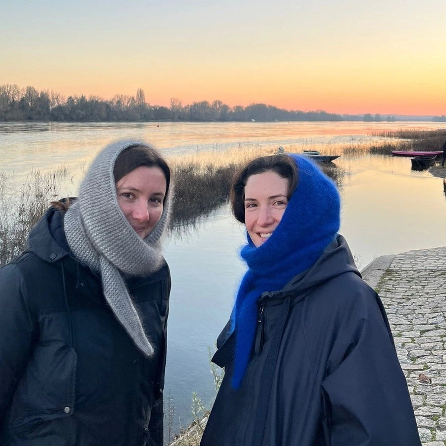 2 femmes portant une écharpe cagoule tricotée devant un fleuve au coucher du soleil