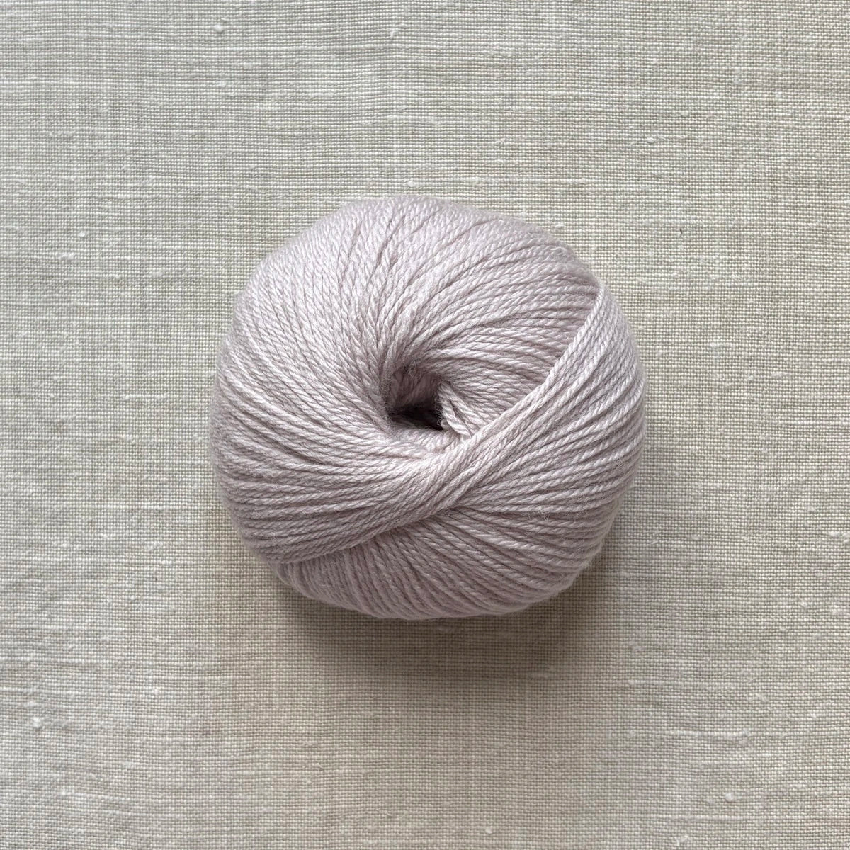 pelote de laine mérinos à tricoter de la marque fonty, de couleur rose argenté sur fond lin beige par tricotant