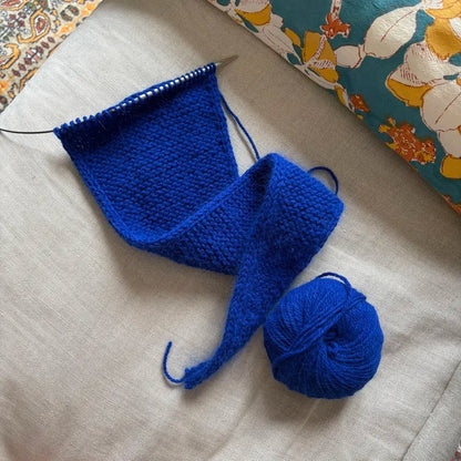 tricot en cours de couleur bleu klein posé sur un canapé en lin beige