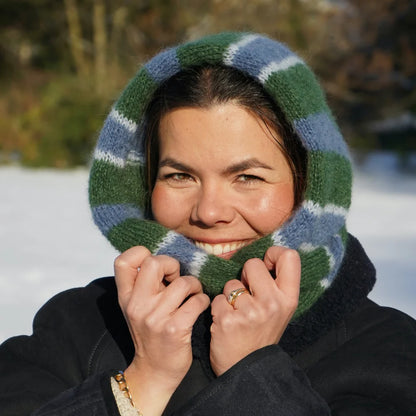 femme souriant avec sur sa tête une écharpe rayée vert et bleu tricotée