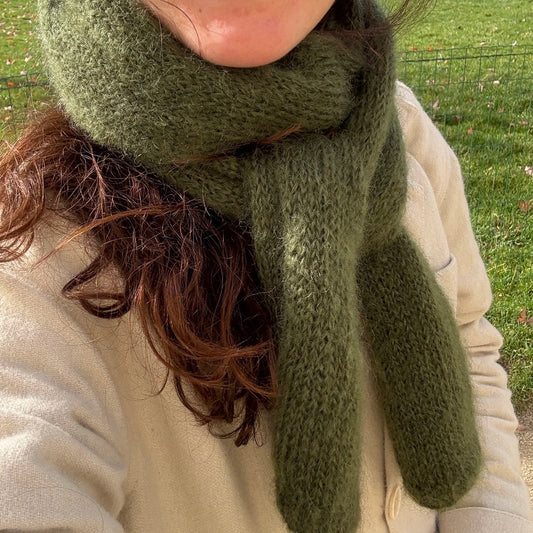 selfie sans visage d'une femme brune portant une écharpe kaki en mohair et une veste écrue dans la nature