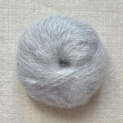 pelote de laine mohair à tricoter de la marque fonty, de couleur gris perle sur fond de lin beige
