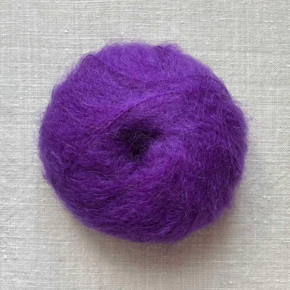 pelote de laine mohair à tricoter de la marque fonty, de couleur violet sur fond de lin beige