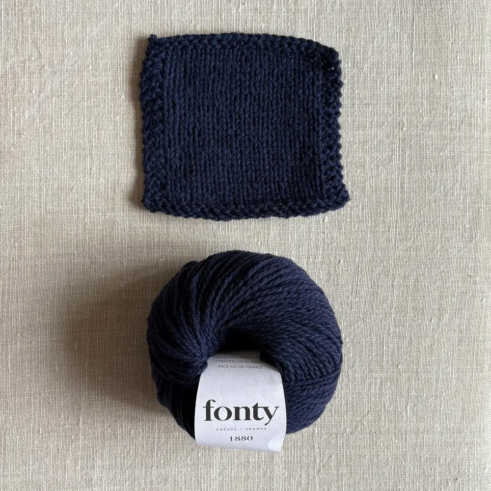 Pelote de laine ethique 1880 coloris bleu marine de Fonty – boutique Tricotant, vue de dessus sur fond lin avec échantillon tricoté