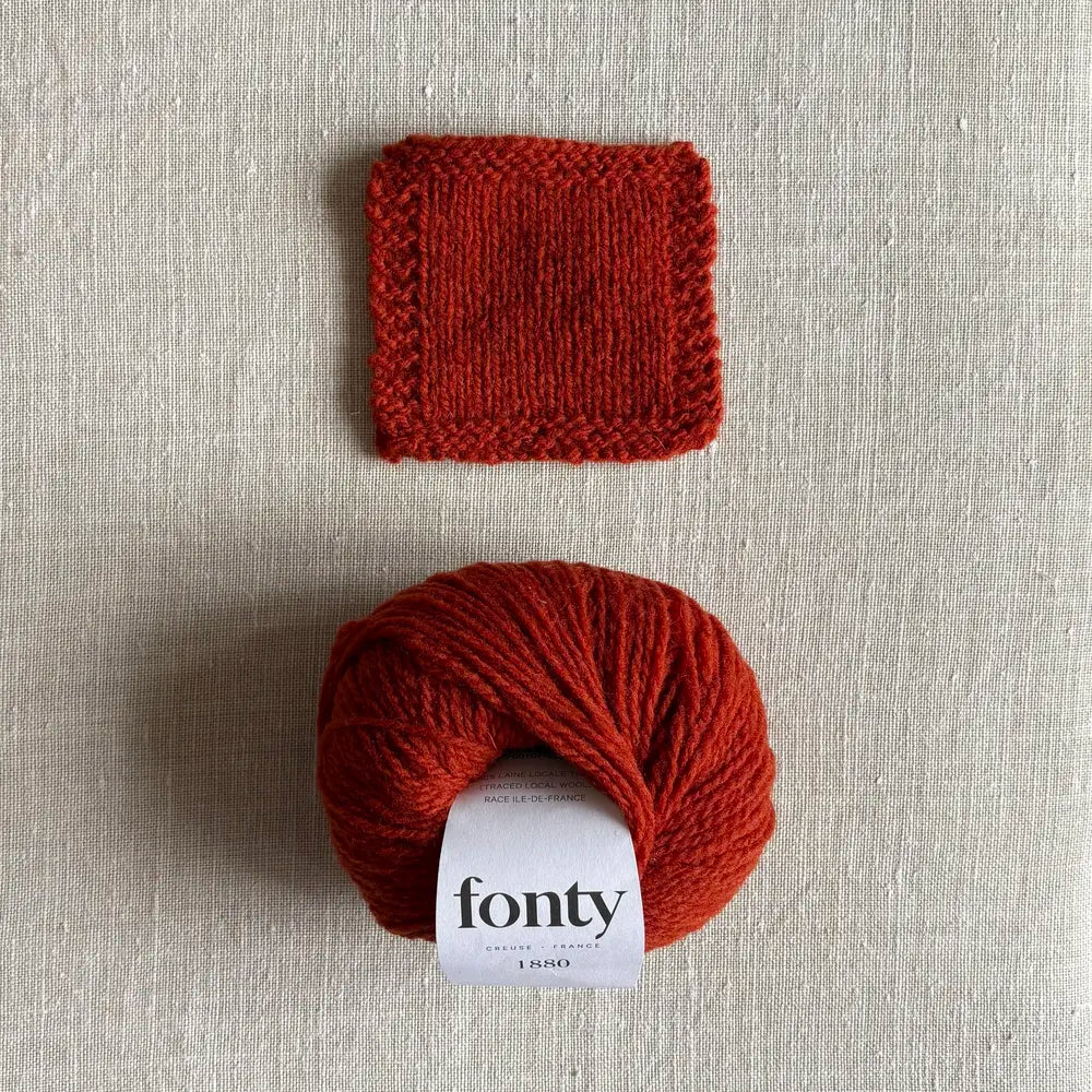 Pelote de laine ethique 1880 coloris rouille de Fonty – boutique Tricotant, vue de dessus sur fond lin avec échantillon tricoté
