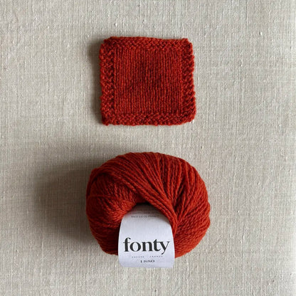 Pelote de laine ethique 1880 coloris rouille de Fonty – boutique Tricotant, vue de dessus sur fond lin avec échantillon tricoté