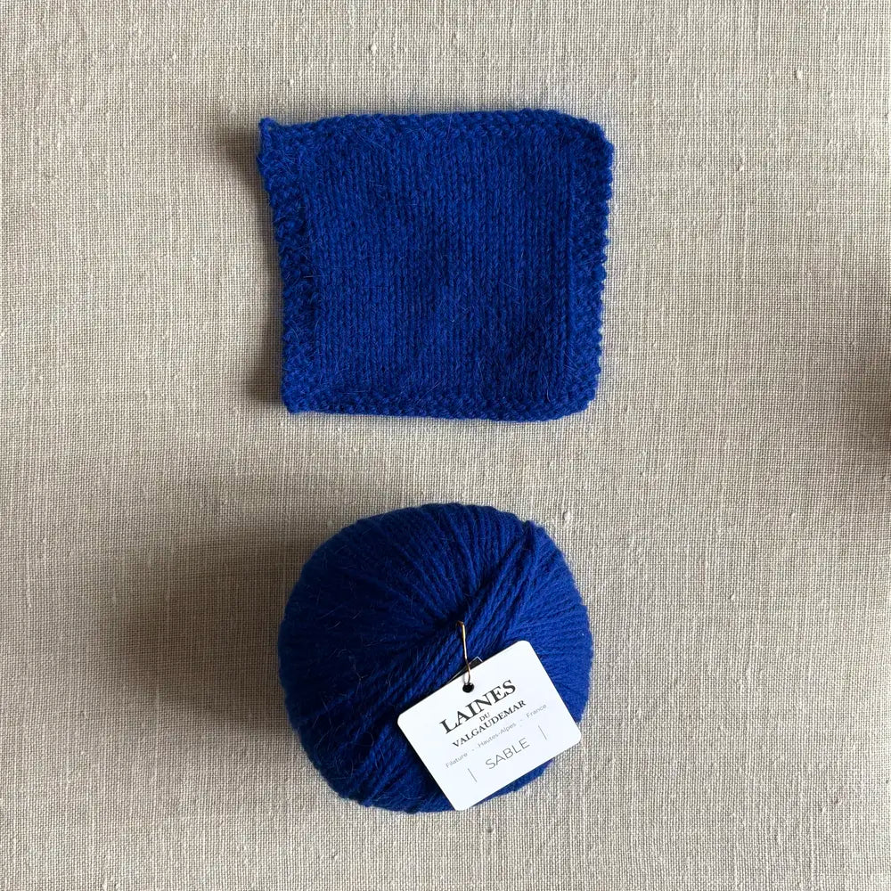 Pelote Sable de laine et angora coloris bleu klein des Laines du Valgaudemar – boutique Tricotant, vue de dessus sur fond lin avec échantillon tricoté