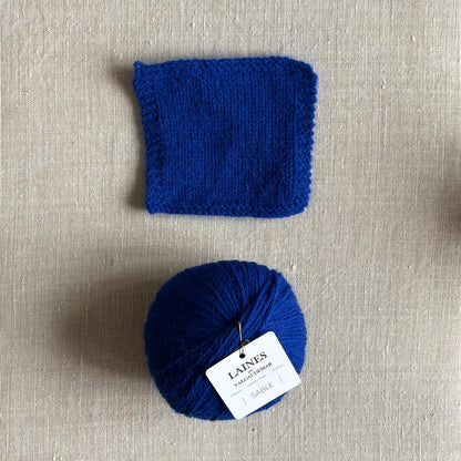 Pelote Sable de laine et angora coloris bleu klein des Laines du Valgaudemar – boutique Tricotant, vue de dessus sur fond lin avec échantillon tricoté