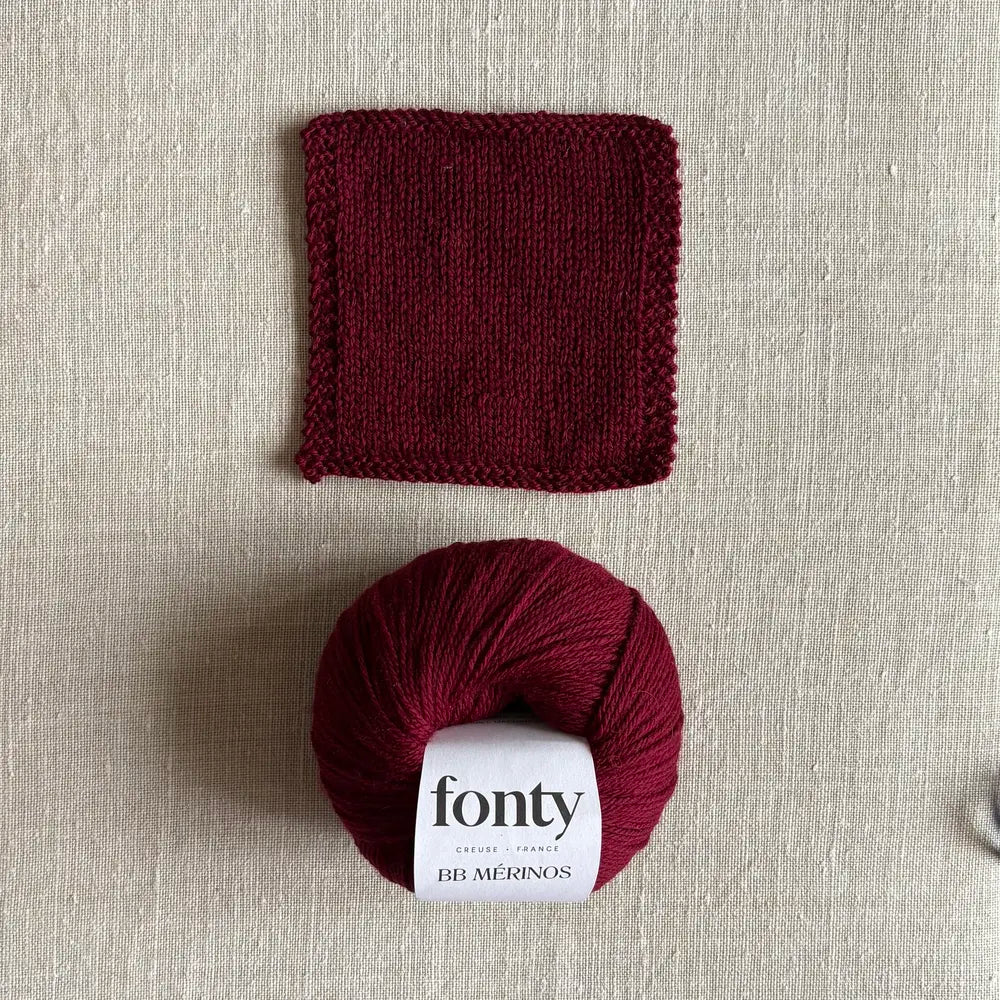 Pelote de laine BB Mérinos coloris bordeaux de Fonty – boutique Tricotant, vue de dessus sur fond lin avec échantillon tricoté