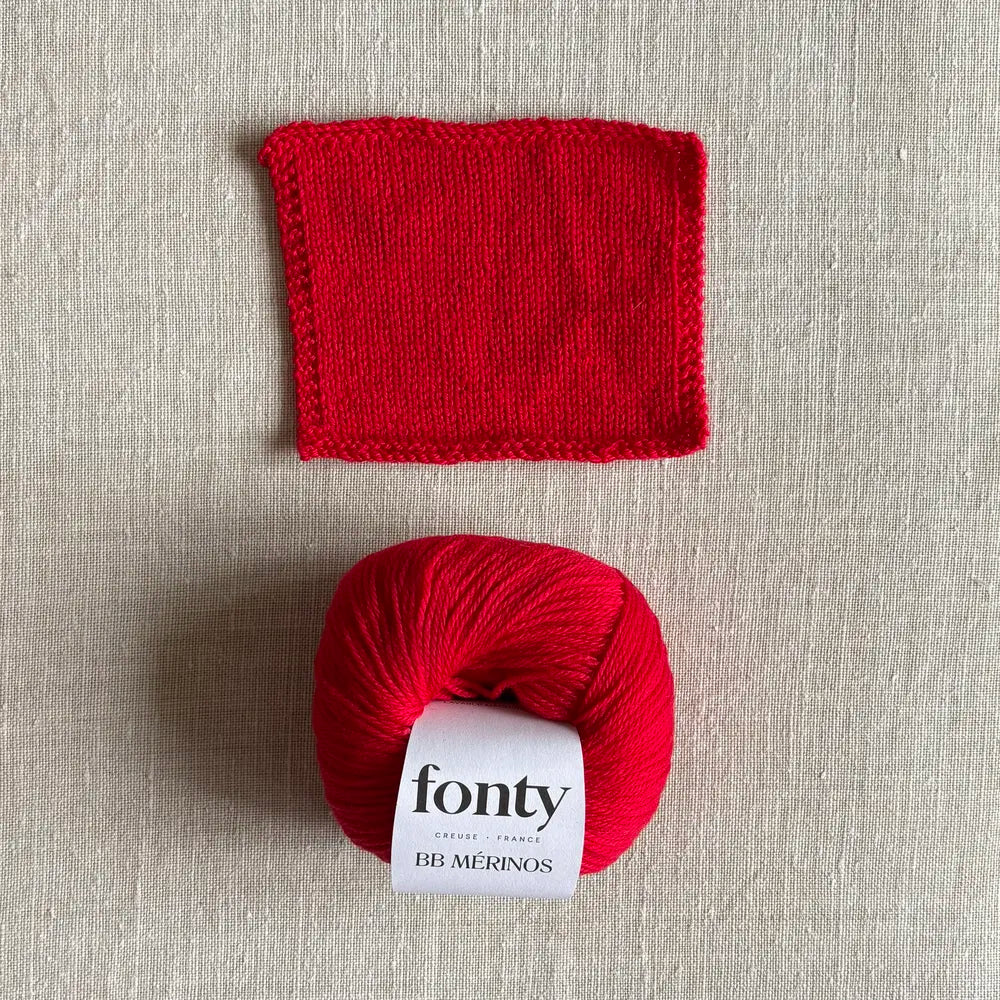 Pelote de laine BB Mérinos coloris rouge vif de Fonty – boutique Tricotant, vue de dessus sur fond lin avec échantillon tricoté