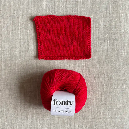 Pelote de laine BB Mérinos coloris rouge vif de Fonty – boutique Tricotant, vue de dessus sur fond lin avec échantillon tricoté