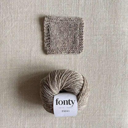 Pelote de laine Fado coloris beige chiné de Fonty – boutique Tricotant, vue de dessus sur fond lin avec échantillon tricoté