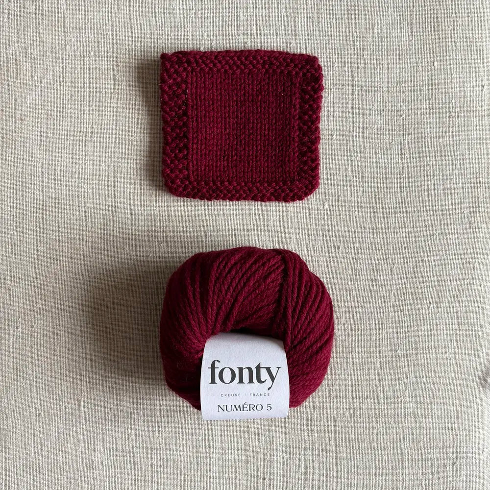 Pelote de laine Numéro 5 coloris bordeaux de Fonty – boutique Tricotant, vue de dessus sur fond lin avec échantillon tricoté