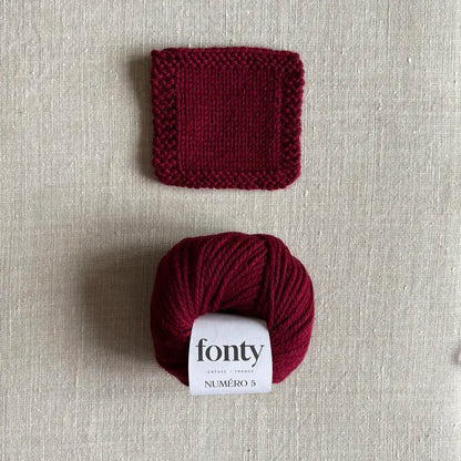 Pelote de laine Numéro 5 coloris bordeaux de Fonty – boutique Tricotant, vue de dessus sur fond lin avec échantillon tricoté