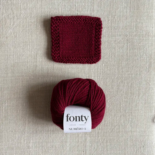 Pelote de laine Numéro 5 coloris bordeaux de Fonty – boutique Tricotant, vue de dessus sur fond lin avec échantillon tricoté