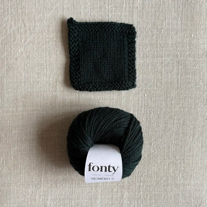 Pelote de laine Numéro 5 coloris vert profond de Fonty – boutique Tricotant, vue de dessus sur fond lin avec échantillon tricoté