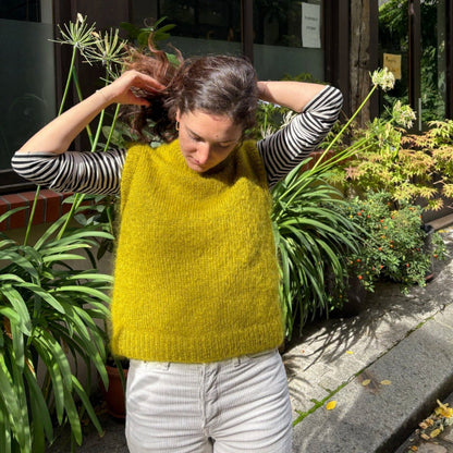 femme portant un pull sans manches tricoté à la main de couleur vert olive