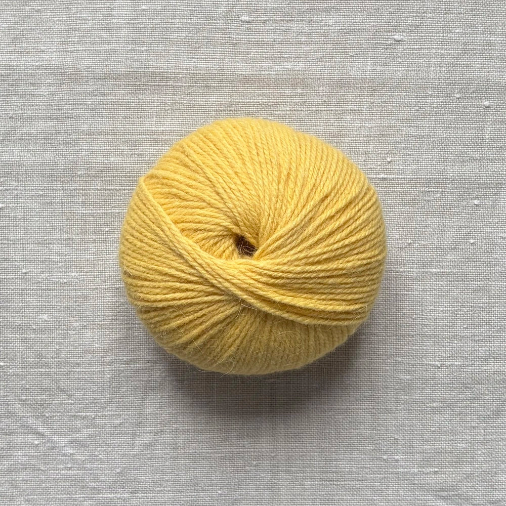 pelote de laine jaune sur fond lin