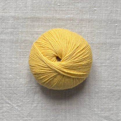 pelote de laine jaune sur fond lin