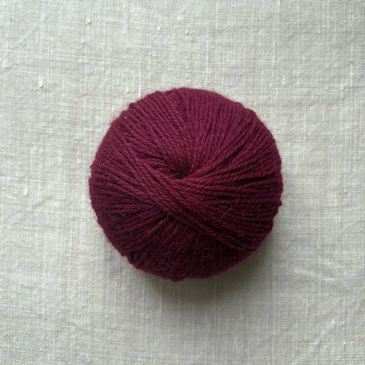 pelote de laine bordeaux sur fond lin