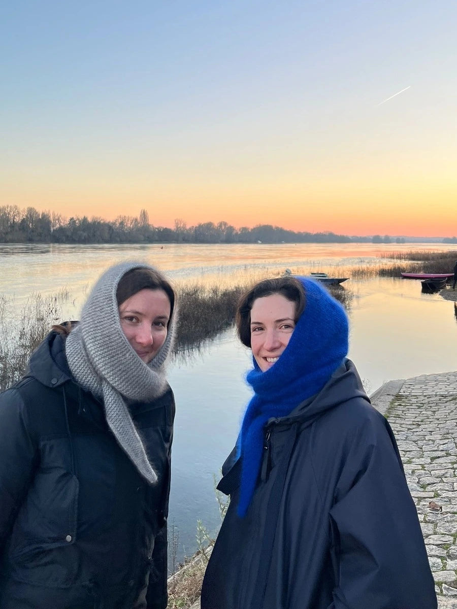 2 femmes portant une écharpe cagoule tricotée devant un fleuve au coucher du soleil